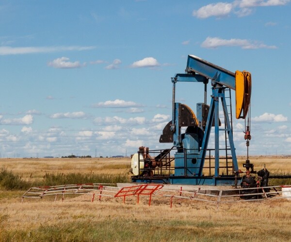 an oil well in the middle of a field with a blue sky