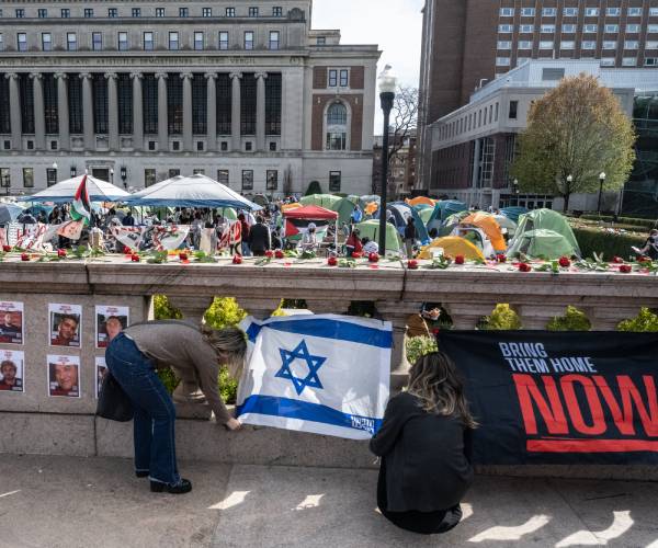 2 woman set up a memorial to israeli hostages with columbia's pro-palestinian encampment in the background