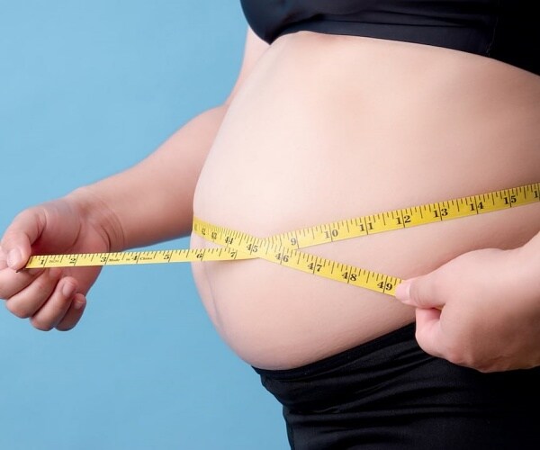 person's waist being measured with a measuring tape