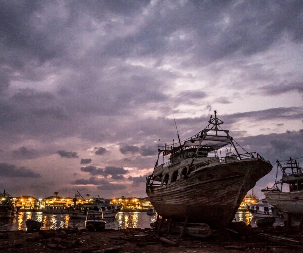 boat sits along nile river with purple skies and city lights in the background