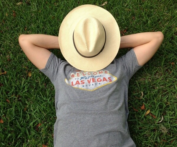 person laying on grass, hat over face, napping