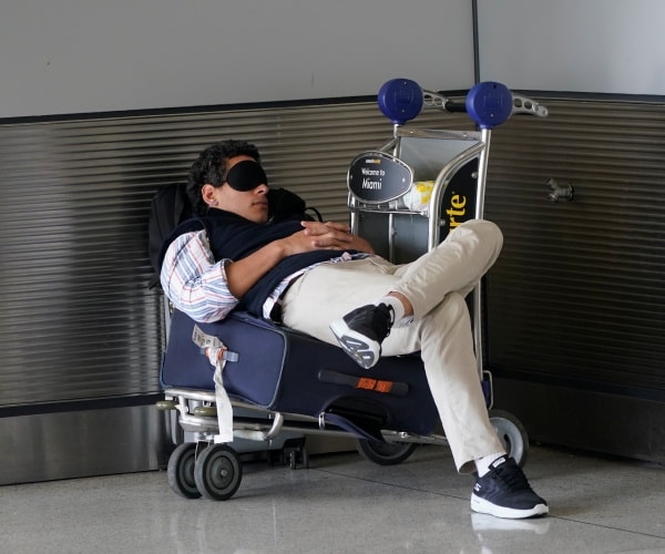 traveler asleep on luggage in airport