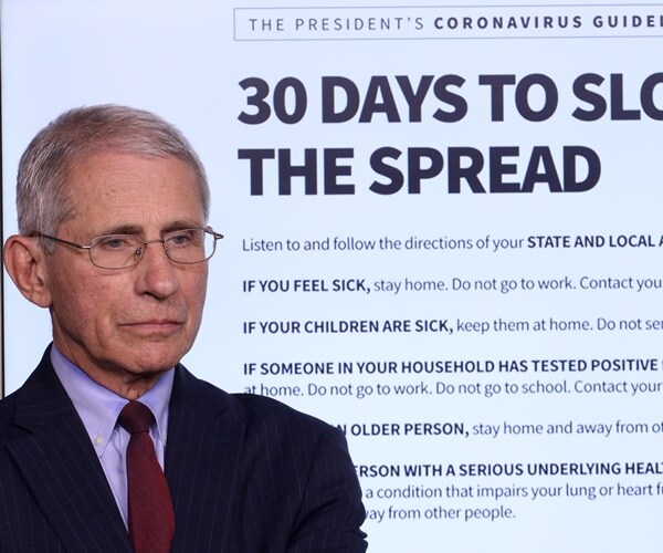 dr. anthony fauci listens to others speak during a coronavirus briefing, in front of projected guidelines