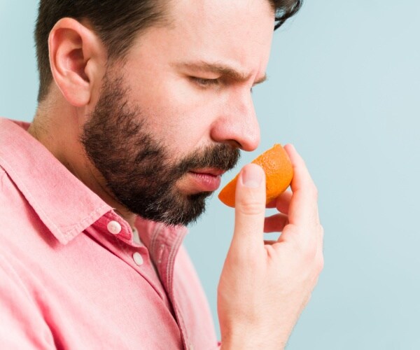 man looking upset because can't smell an orange