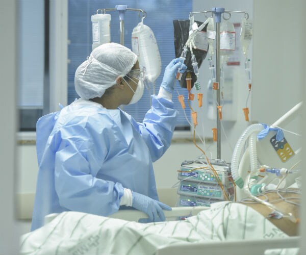 a health worker is shown looking at an icu patients' meds