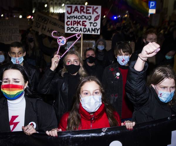 marchers carry signs and a coat hanger