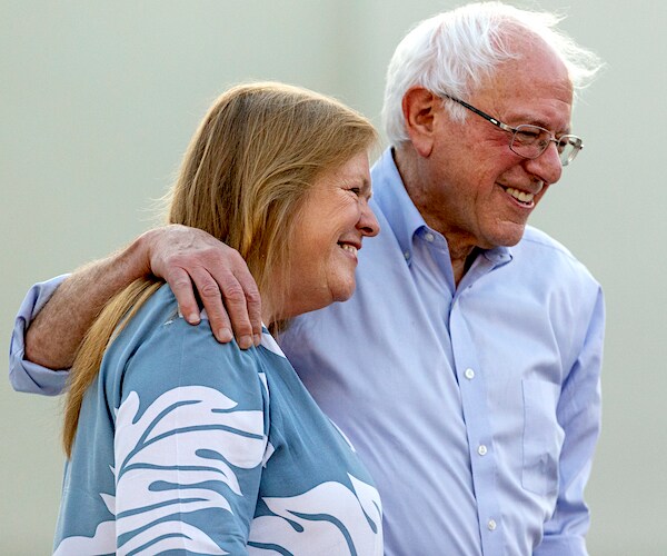 jane and bernie sanders smile as they walk jane under his left arm