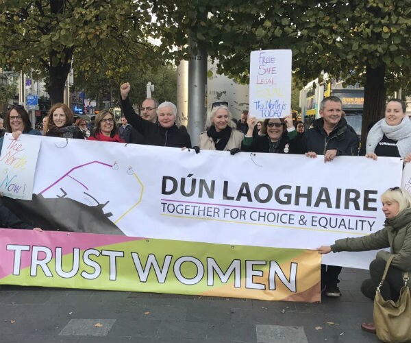 people hold a banner celebrating the change in laws in northern ireland