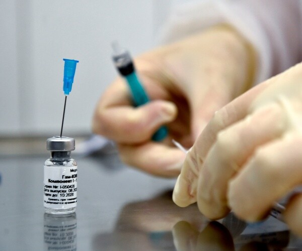 nurse wears gloves with a bottle of the vaccine placed nearby