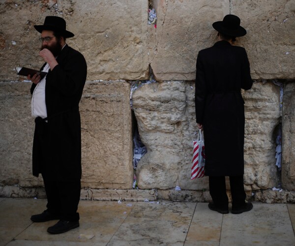 jewish men pray at the western wall in jerusalem