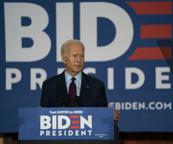 joe biden speaks in iowa at a podium displaying his campaign materials on the podium and in the background