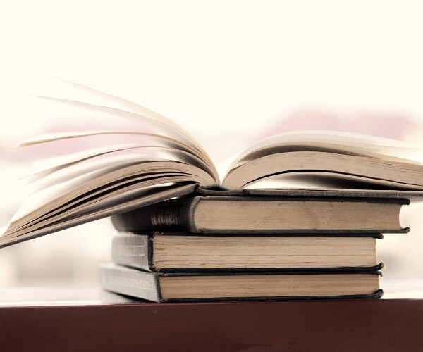 open book sitting on pile of books