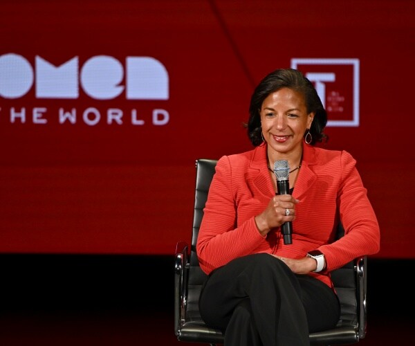 susan rice in an orange blazer and black pants sitting on stage