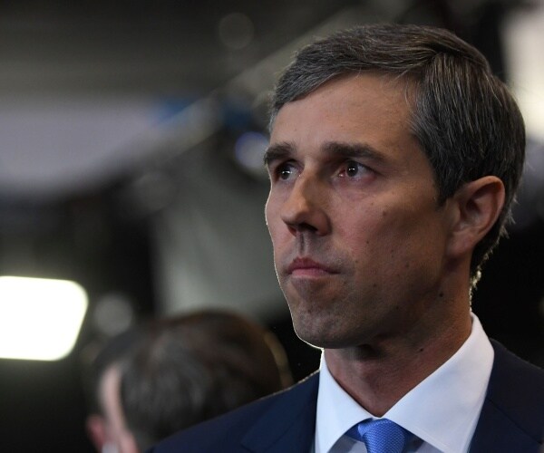 beto in a suit and blue tie turning his head to the side