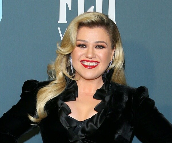 kelly clarkson stands on blue carpet
