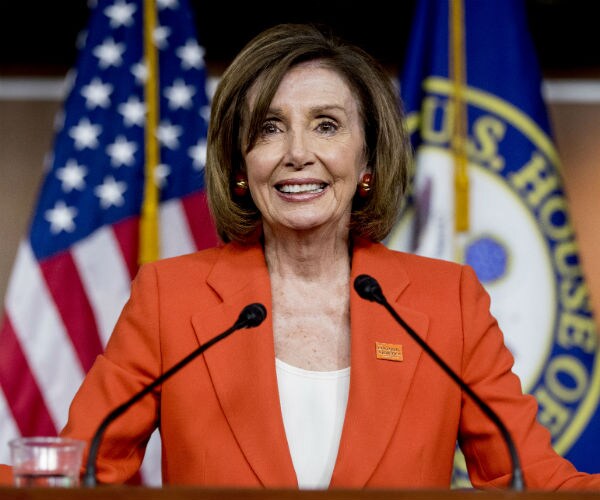 house speaker nancy pelosi is shown in an orange suit with the us flag in the background