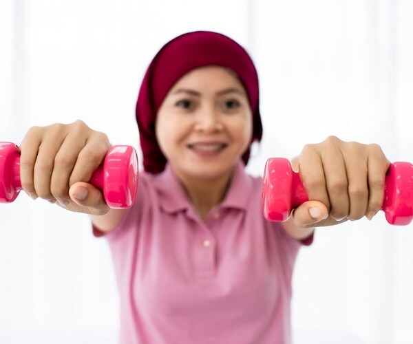 woman with cancer lifting pink weights