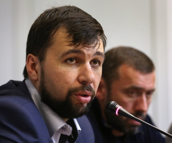 denis pushilin speaks into a microphone
