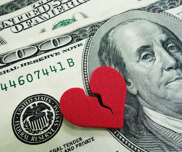 closeup of a broken red heart on cash - divorce concept 
