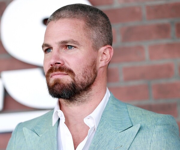 stephen amell stands on red carpet