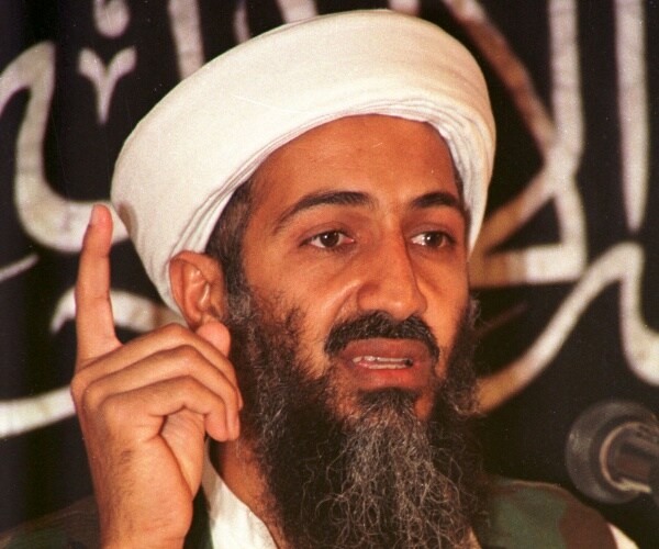 osama bin laden in a white turban pointing his finger up
