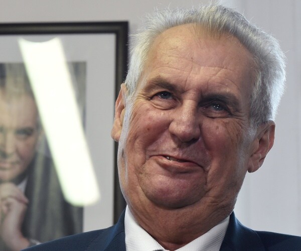 zeman in a suit with a portrait of himself behind him
