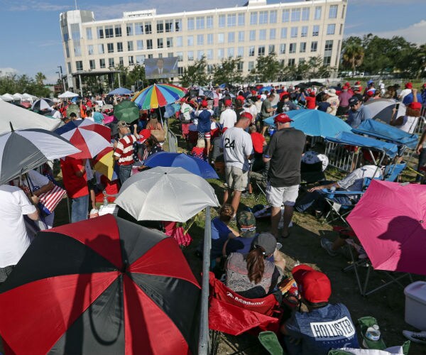 supporters of president donald trump wait in line in orlando, holding umbrellas 