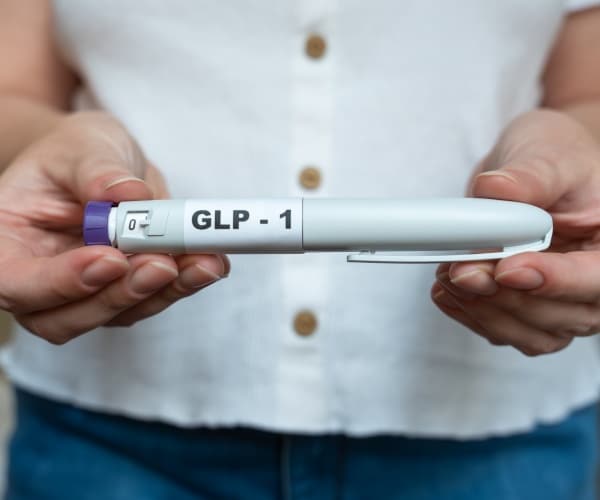 woman holding a cartridge that says GLP-1 on it