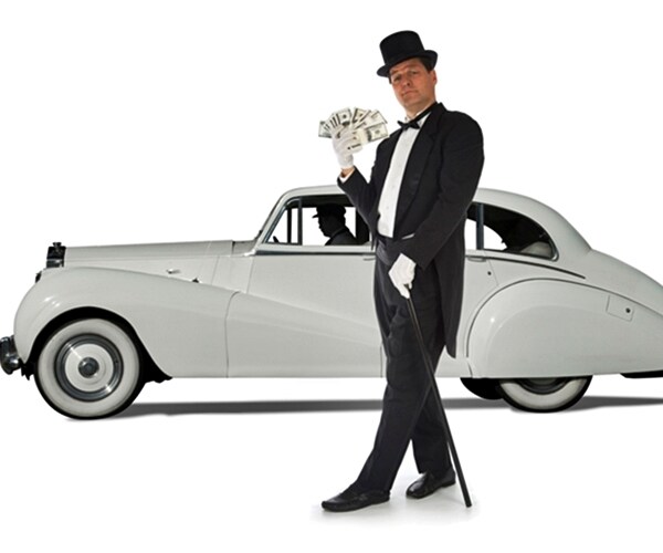 billionaire standing in front of a vintage car against a white background