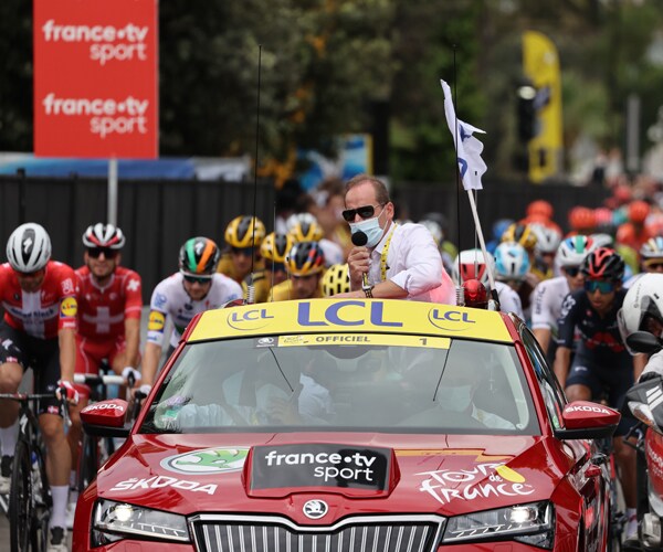 tour de france director christian prudhomme stands up through a car sunroof at the start of a stage