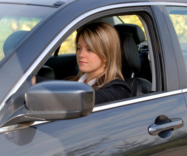 woman sitting in car in work clothes