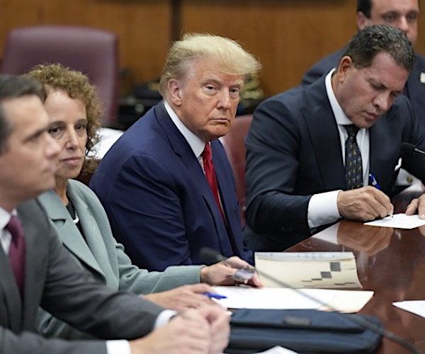 trump sitting at the defendants table with his lawyers