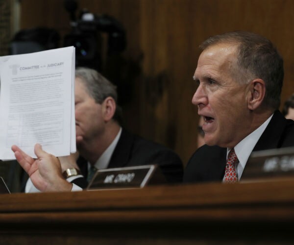 Sen. Thom Tillis is shown holding up committee documents on capitol hill