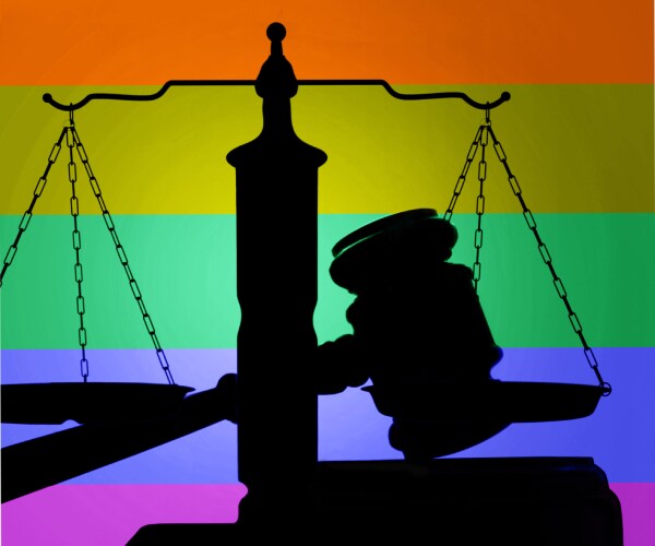 a rainbow flag behinda judges gavel and the scales of justice