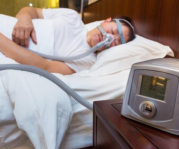 man sleeping in bed with cpap machine