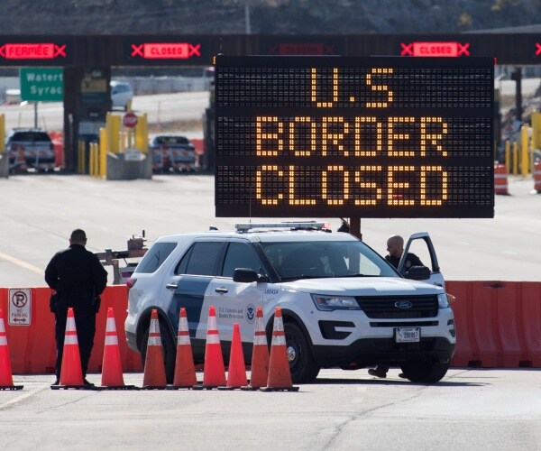 us canada border is shown with a customs officer standing by traffic cones