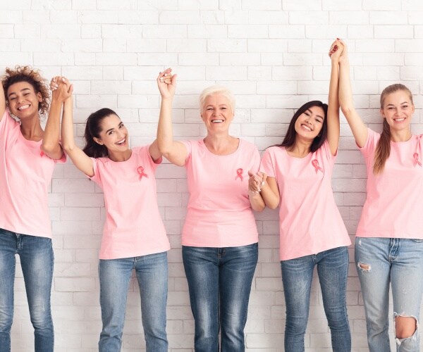 breast cancer survivors in pink shirts holding hands, happy