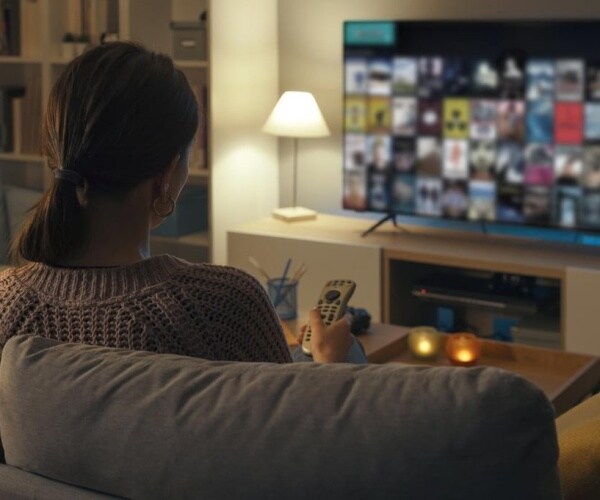 woman on couch at night with remote in front of large screen television