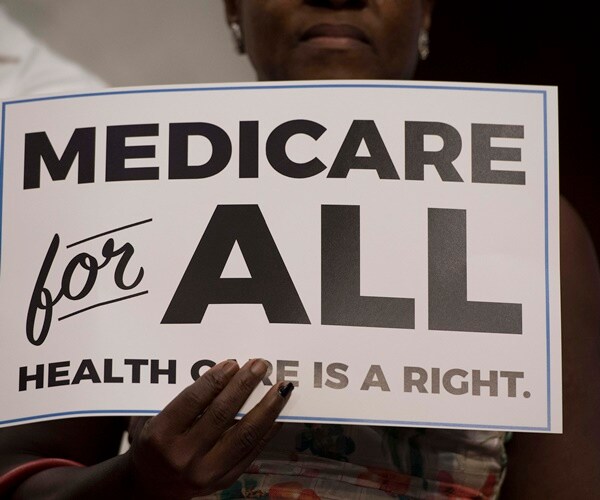 a sanders supporter holds up a medicare for all sign