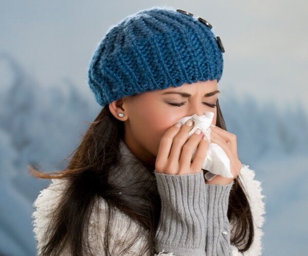 woman outside in winter sneezing