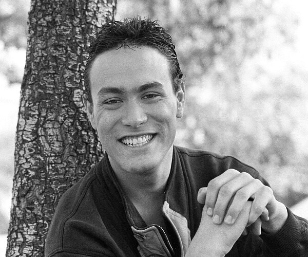 brandon lee smiles while sitting in front of tree