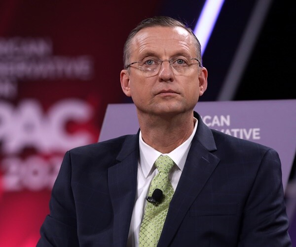 doug collins sitson a stage at cpac
