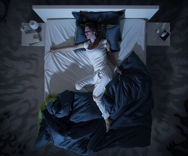 woman in bed at night with covers off to the side
