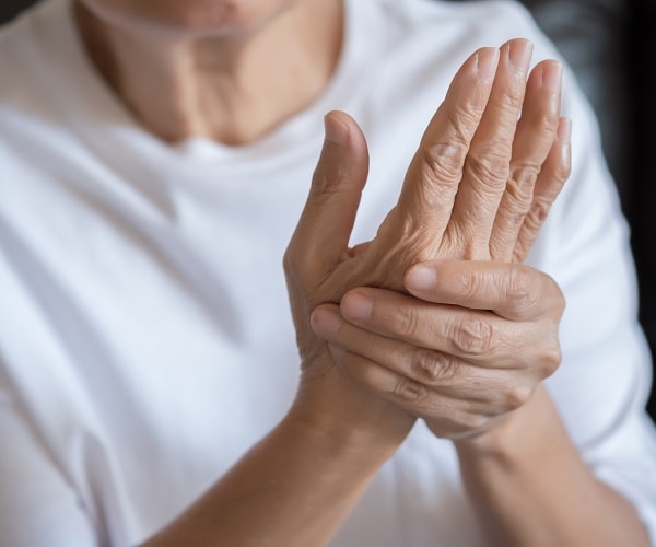 older woman holding her hand