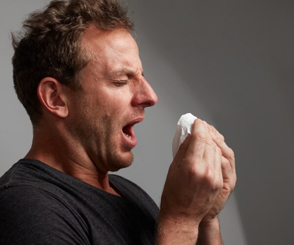 man with cold sneezing