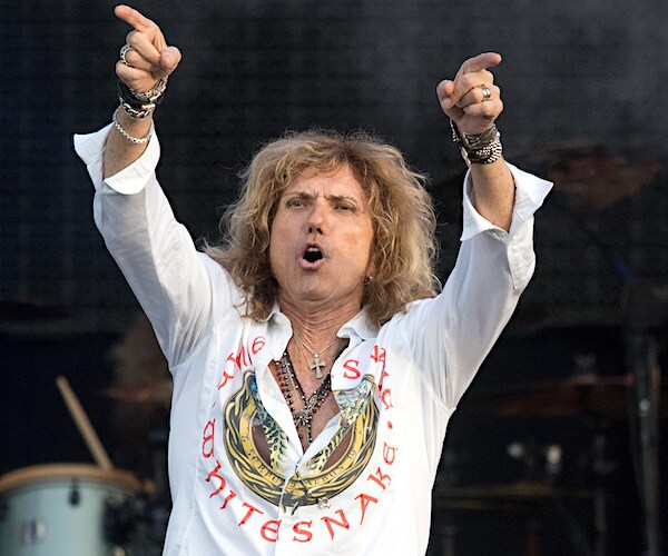 whitesnake's david coverdale raises both hands above his head and points to the crowd after a show