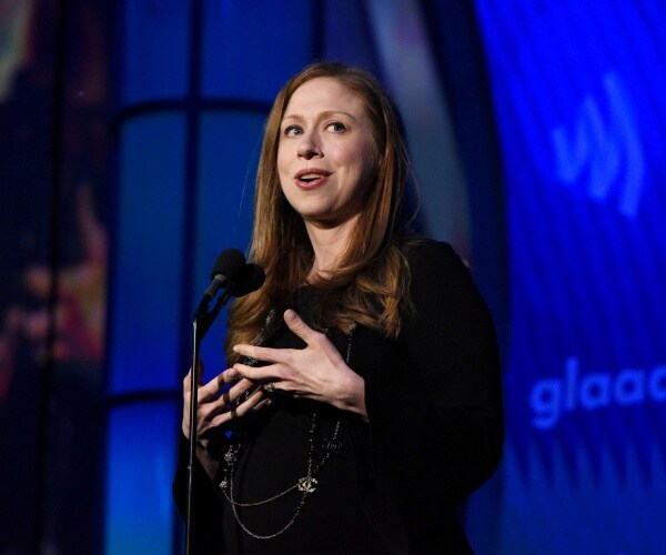 clinton in a black dress speaking on stage into a mic