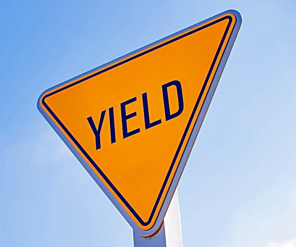 yellow yield sign with a blue sky background