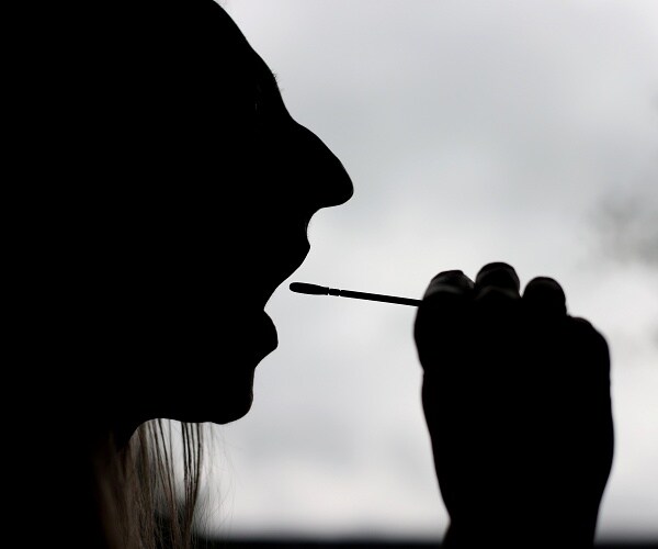 woman starts to swab mouth for covid  home test