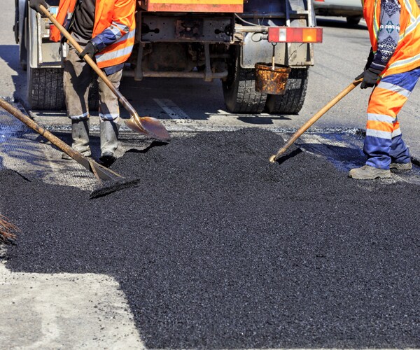 workers spreading hot asphalt on a road